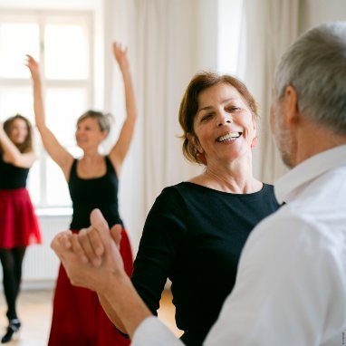 A group of senior people attending dancing class with dance teacher.